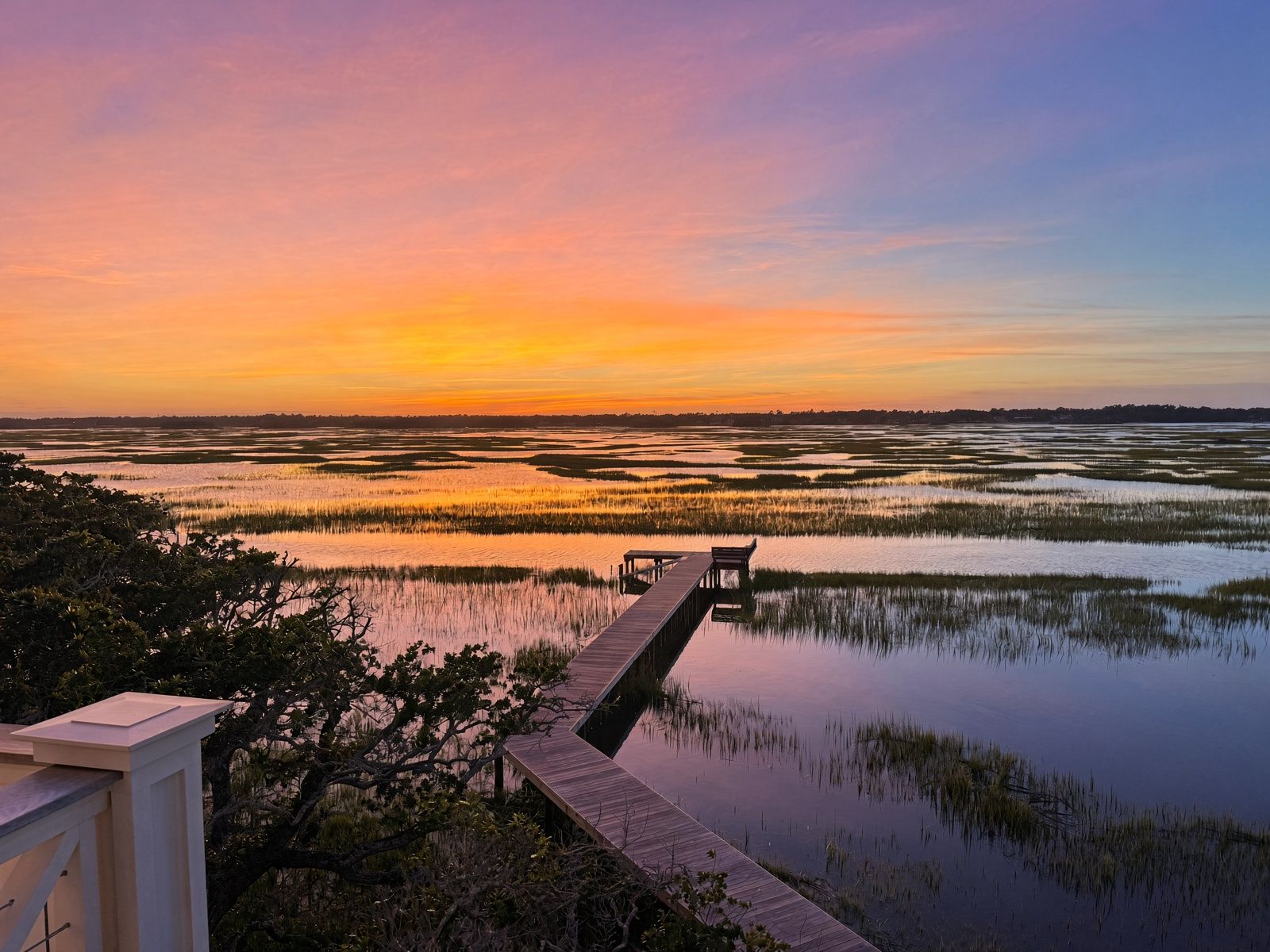 Colorful sunset reflected across the marsh and private dock