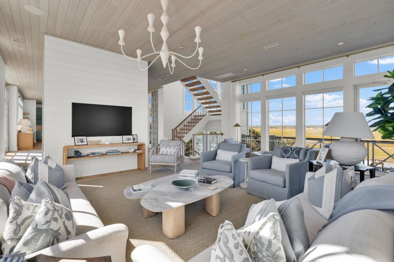 Main living room with white sofas, vaulted ceiling and expansive windows