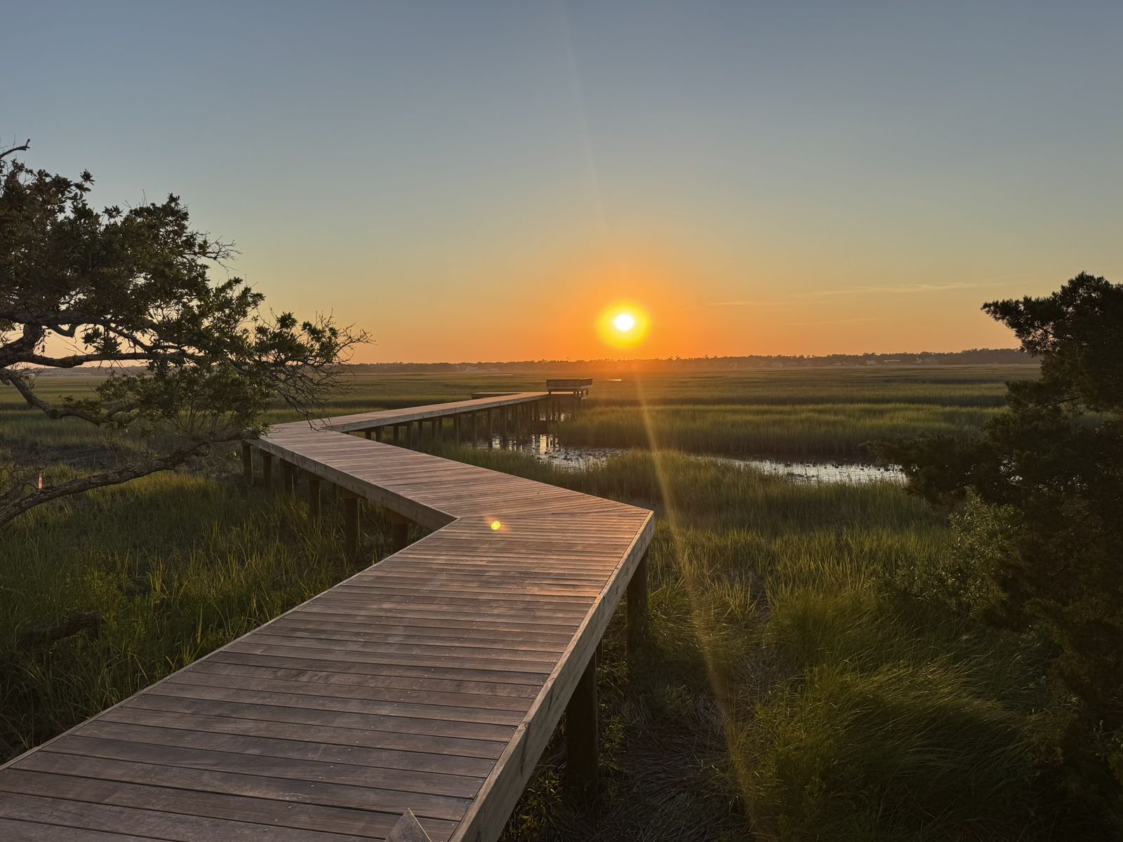 Private dock extending across the marsh toward the sunset