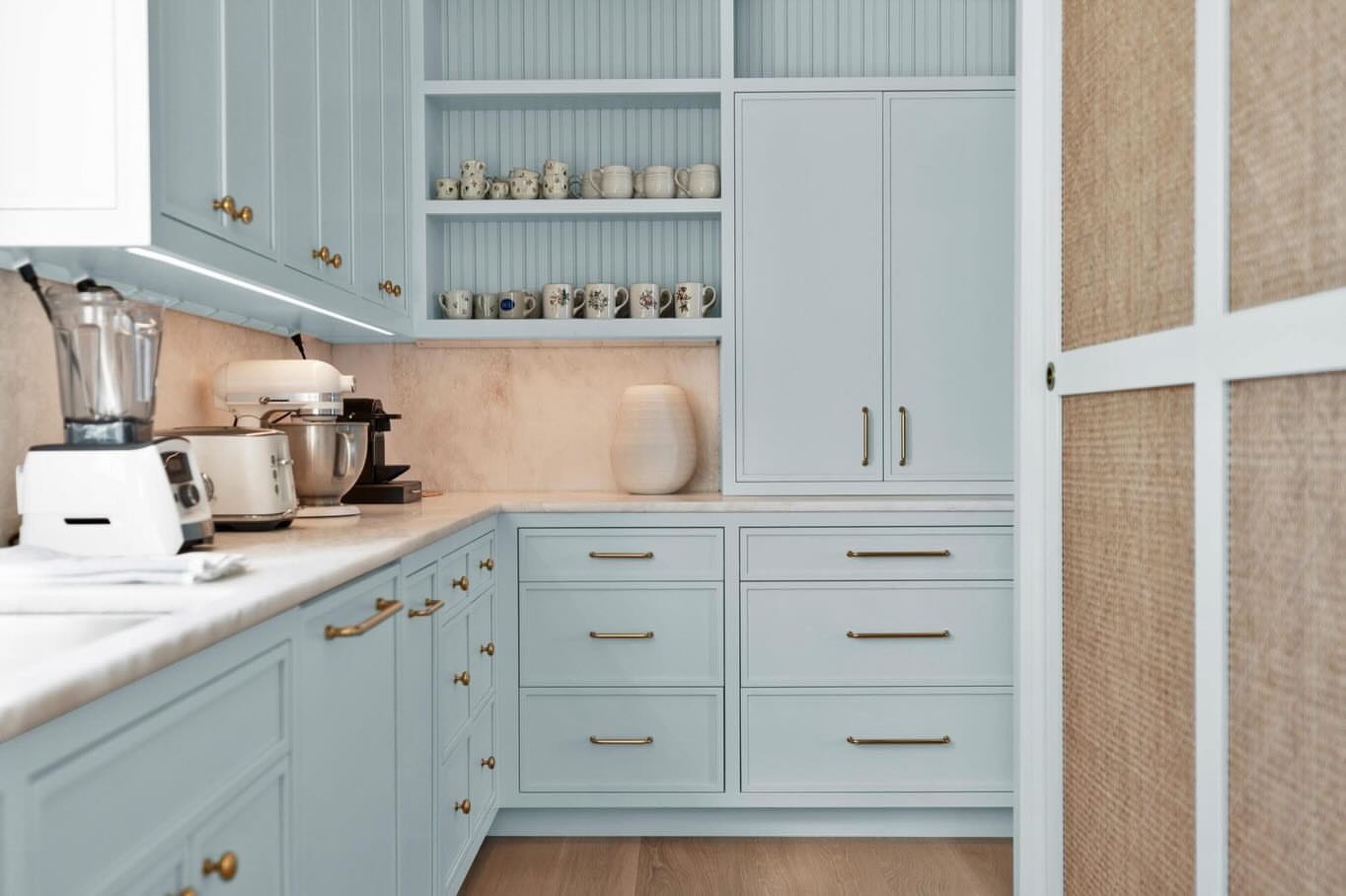 Pale blue butler's pantry with brass hardware