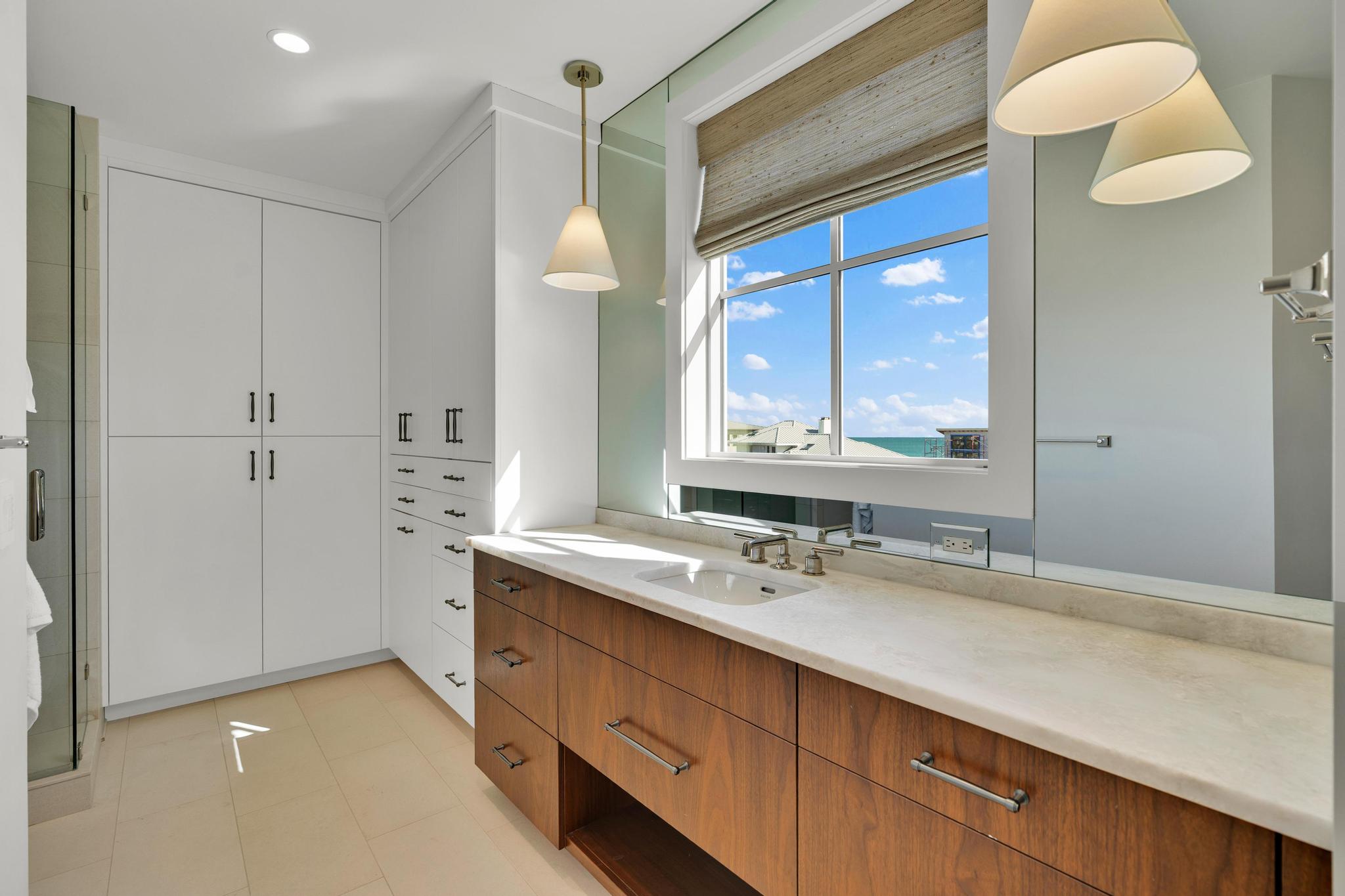 His bath with a wood vanity, ocean-view window and wardrobes