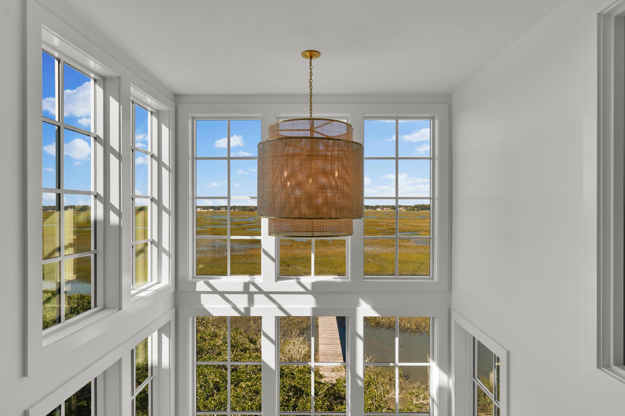 Stair-tower window with a woven chandelier overlooking the marsh